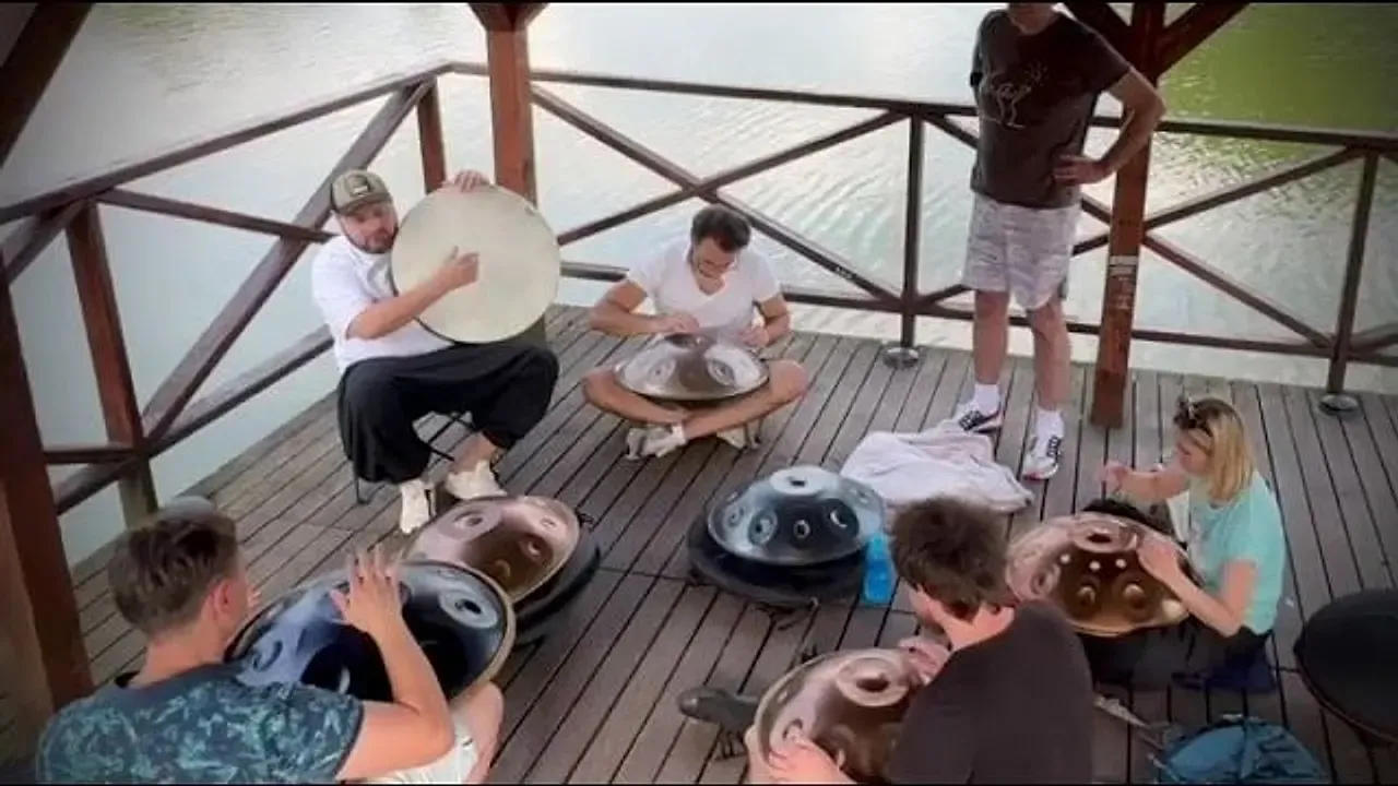 Kadr z filmu: uczestnicy 8. spotkania Handpan Łódź grają na handpanach na molo nad stawem w Zgierzu